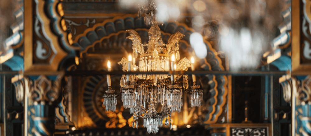 Ornate glass chandelier illuminating a gilded room with warm ambient ligh